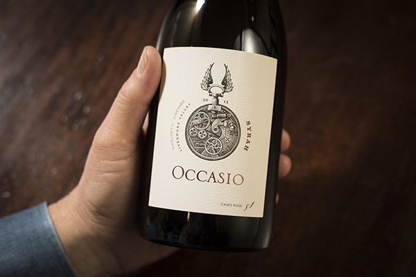 bottle of occasio syrah wine in a persons hand