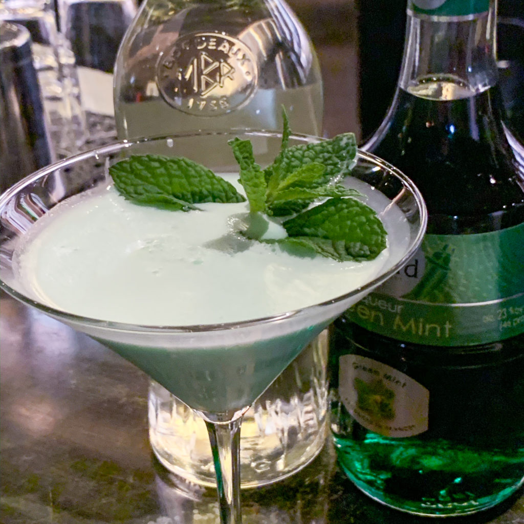 photo of a grasshopper cocktail in a martini glass with sprig of mint garnish