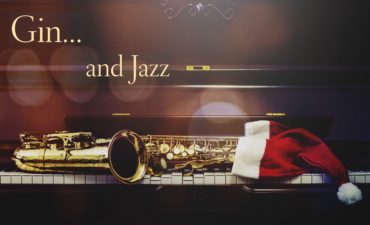 a photo of a saxophone on keyboard with a Santa hat and caption gin and jazz