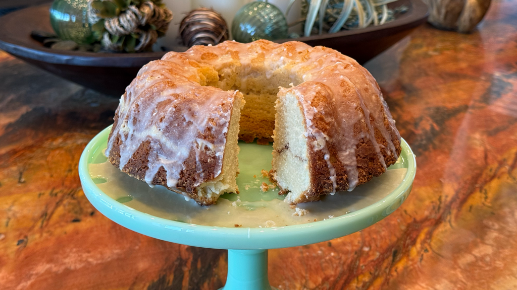 a bundt cake with sugar frosting and slice taken out on a green cake plate