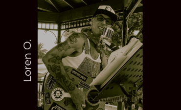 guitarist Loren O with guitar, baseball cap, and music stand