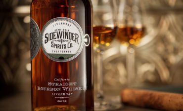 bourbon bottle with partially filled snifter against a tin tile backdrop