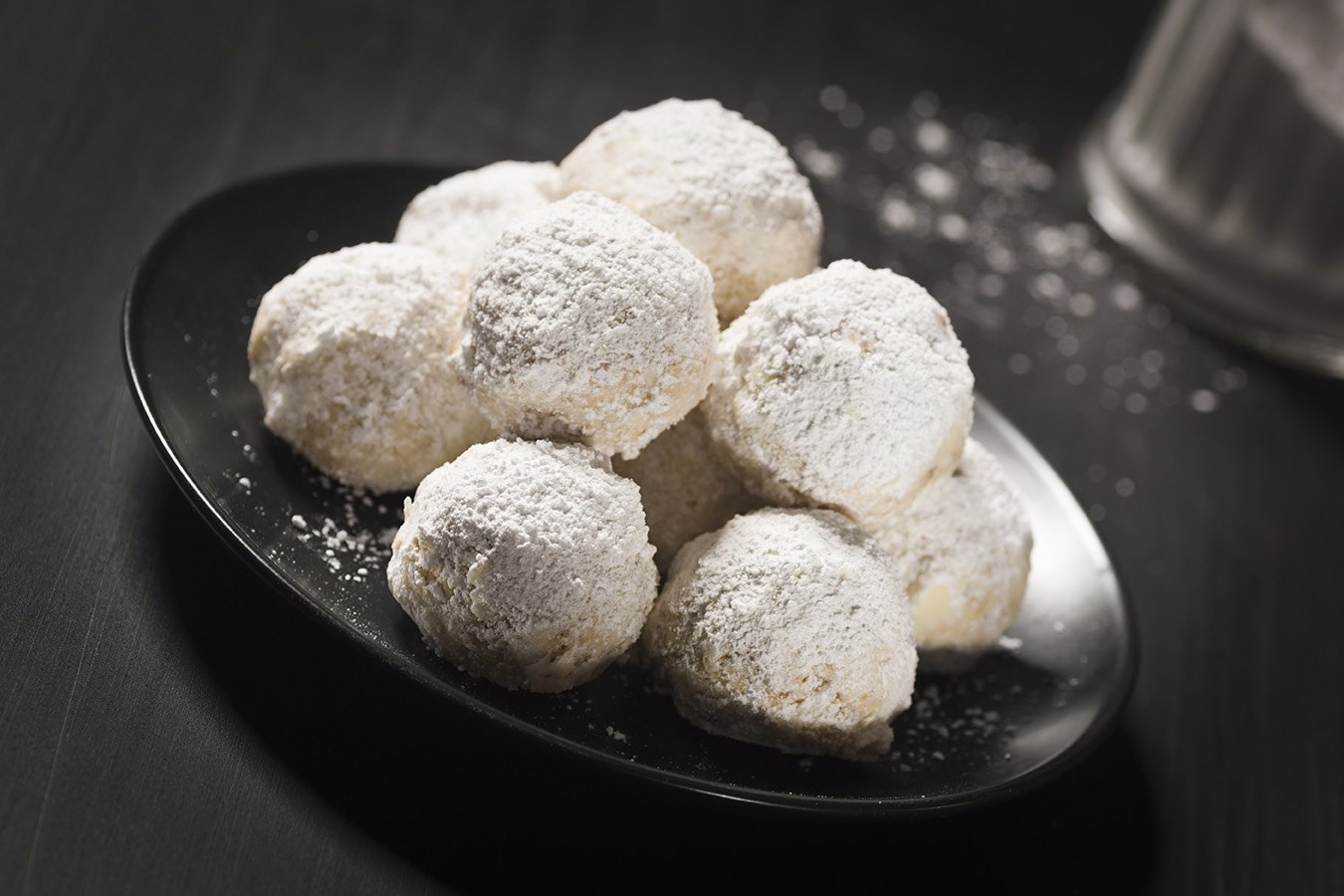 RUSSIAN TEA CAKE COOKIES ON A BLACK DISH AND WOODEN TABLE