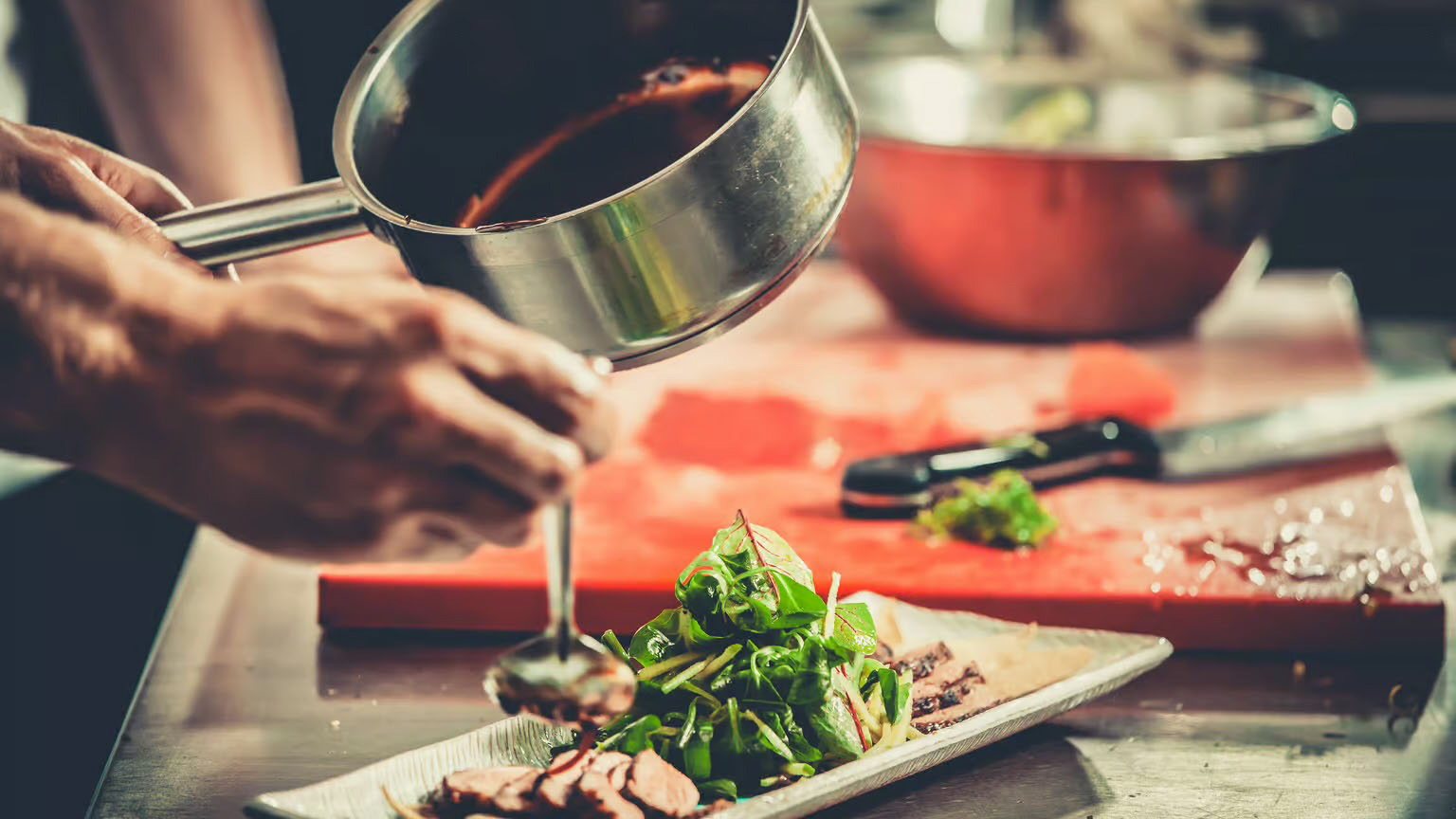 A steak salad with greens being plated